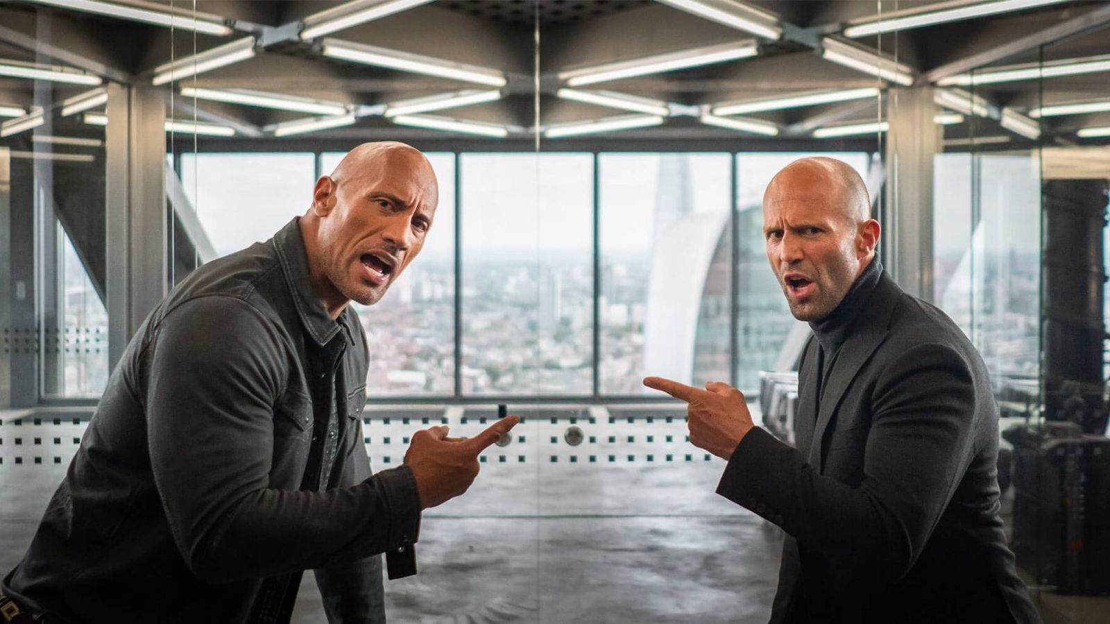 Dwayne Johnson and Jason Statham point aggressively to one another in Hobbs and Shaw