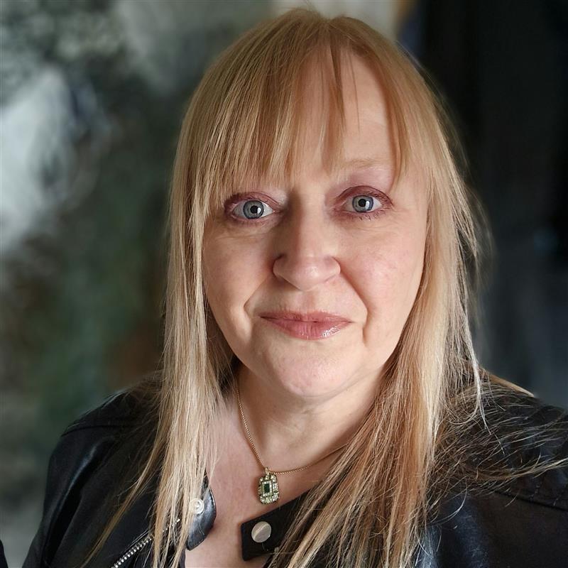 A woman with blonde hair and a fringe is shown from shoulders up.