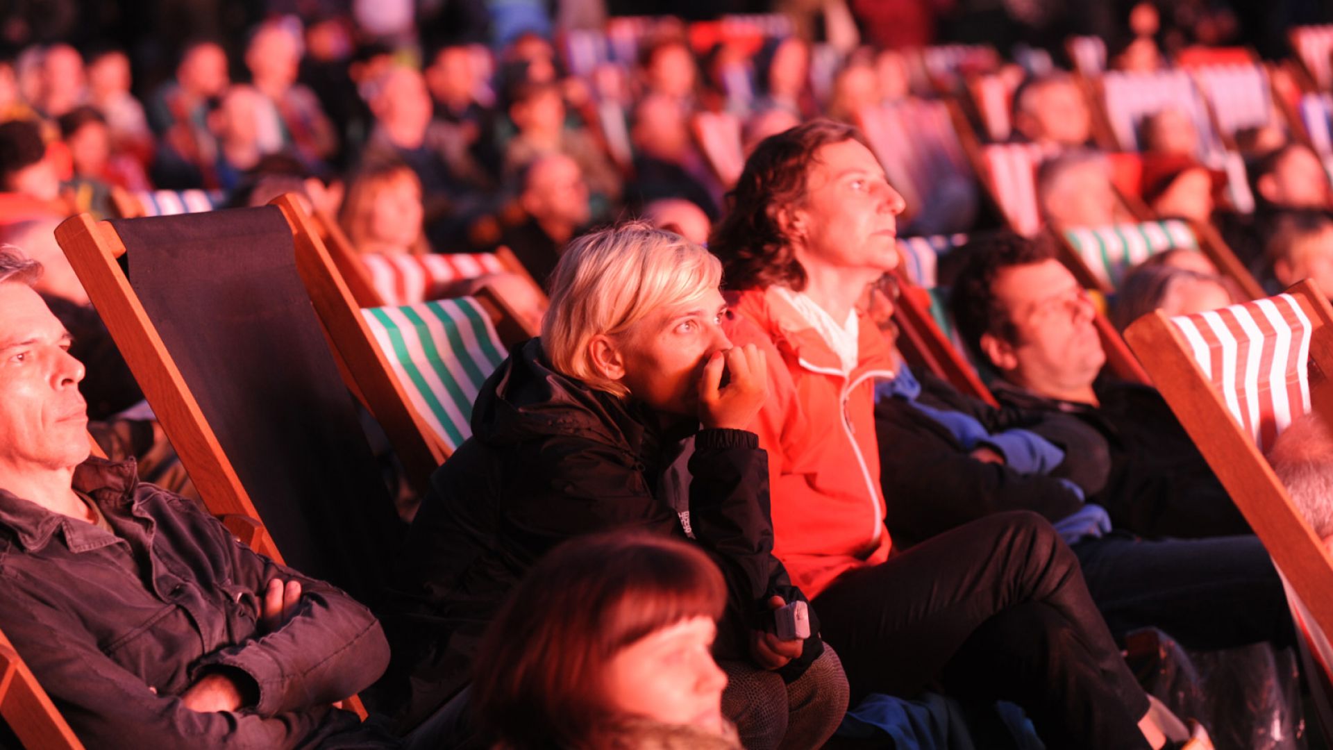 People sitting in deckchairs watching an outdoor screening at night