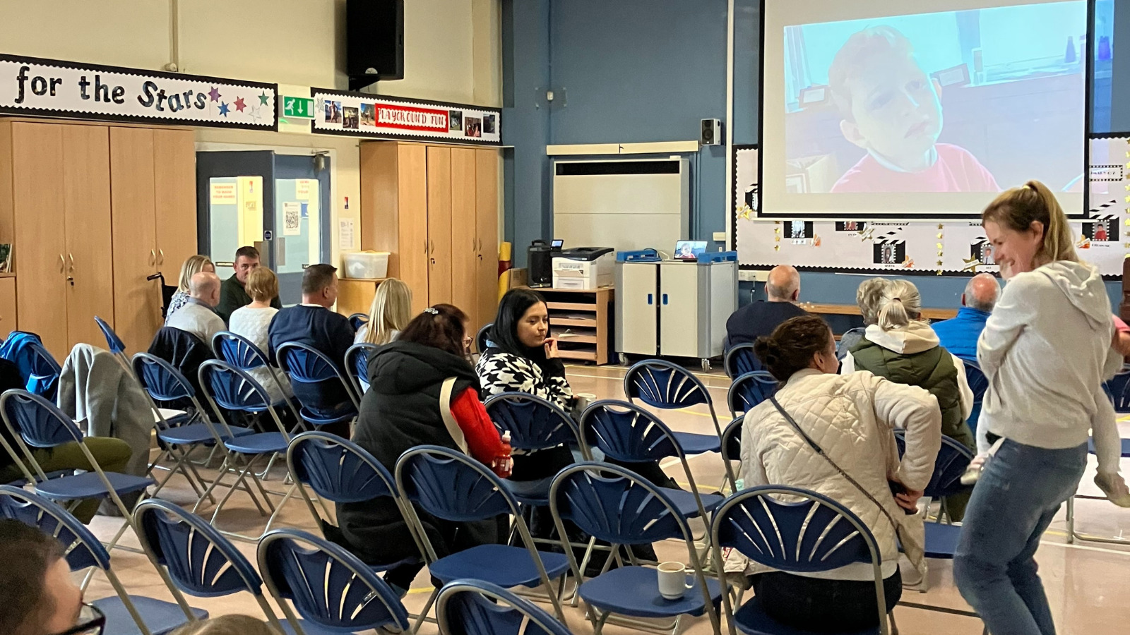 Parents and pupils in classroom with students work being projected on large screen.