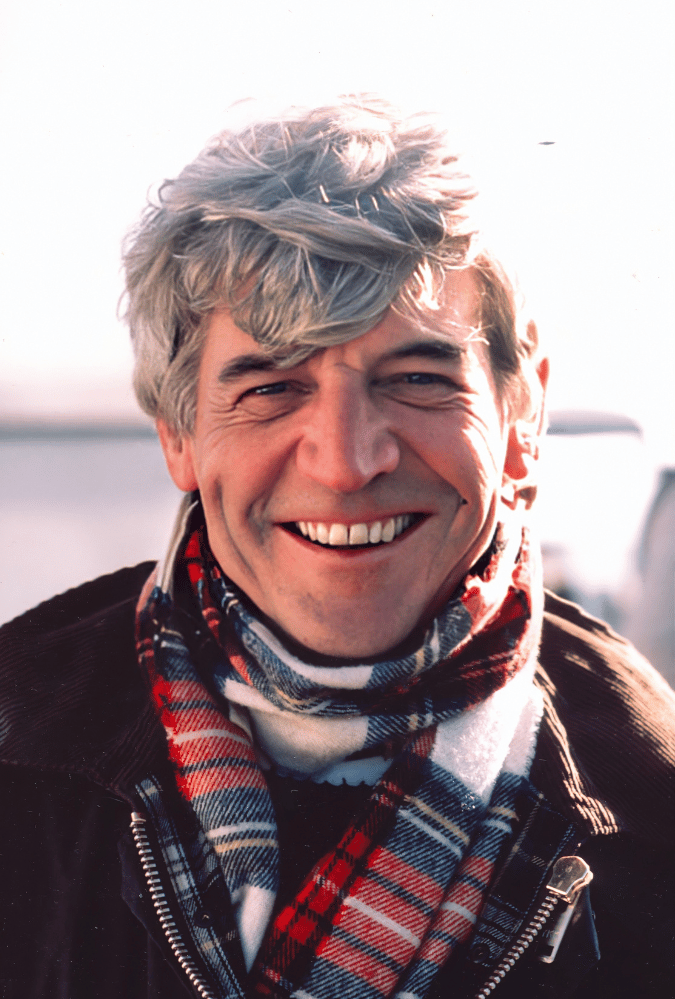 Bill Douglas smiling wearing a tartan scarf.