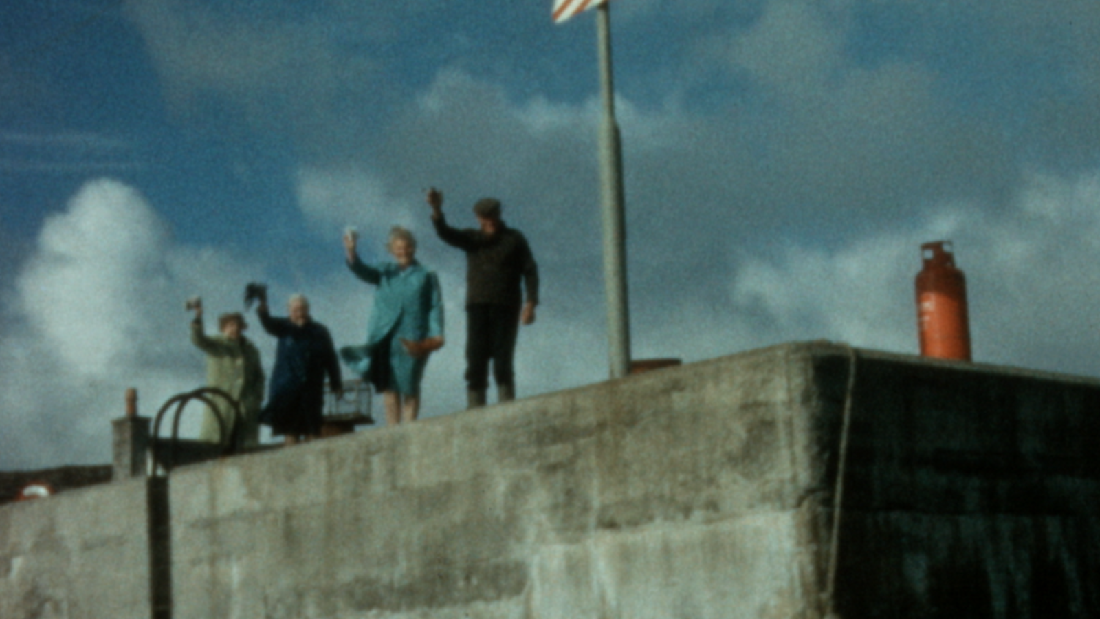 Old video footage from Dùthchas. People waving on a harbour.