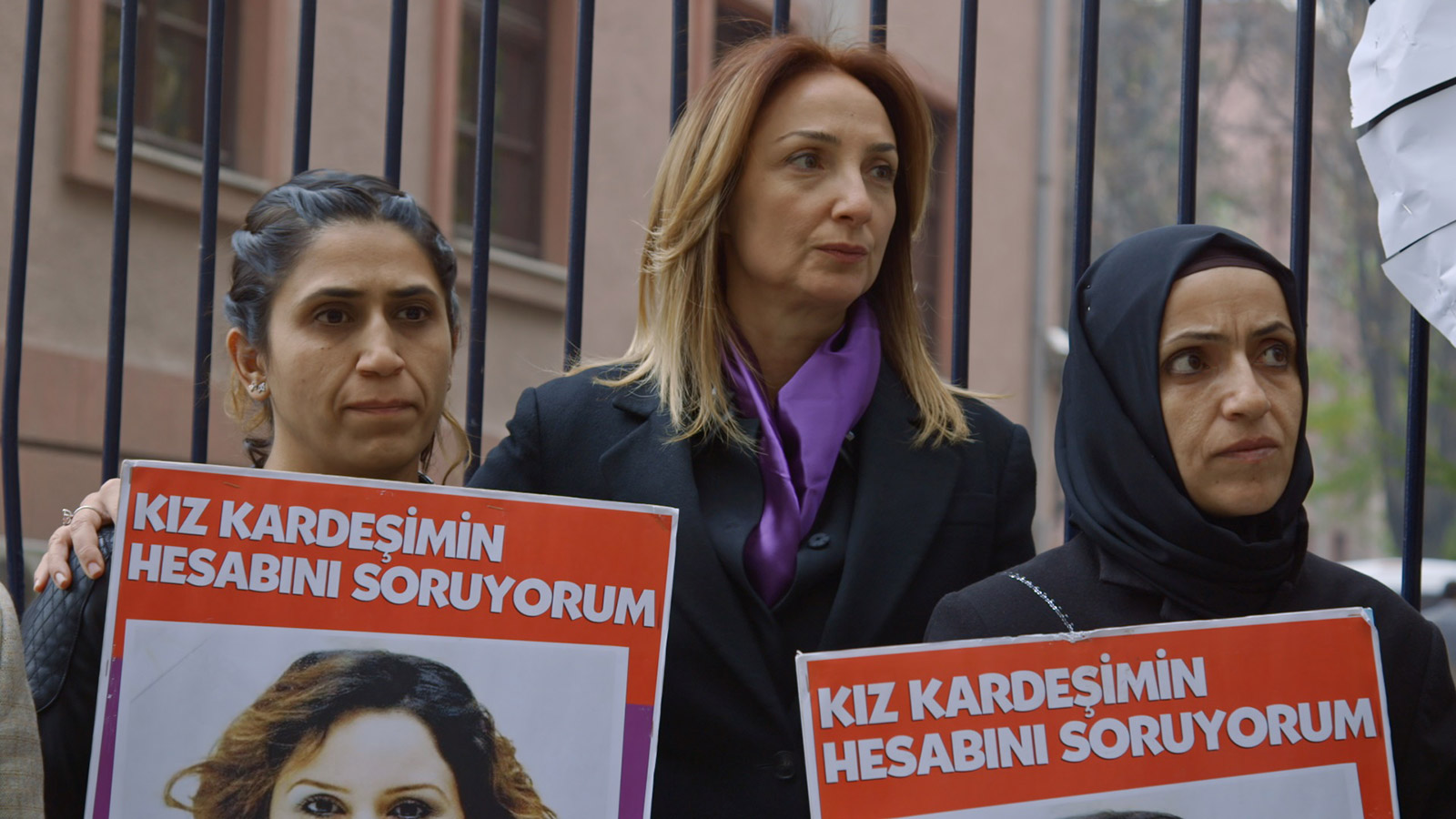 Still from Dying to Divorce. Three woman hold signs at a protest