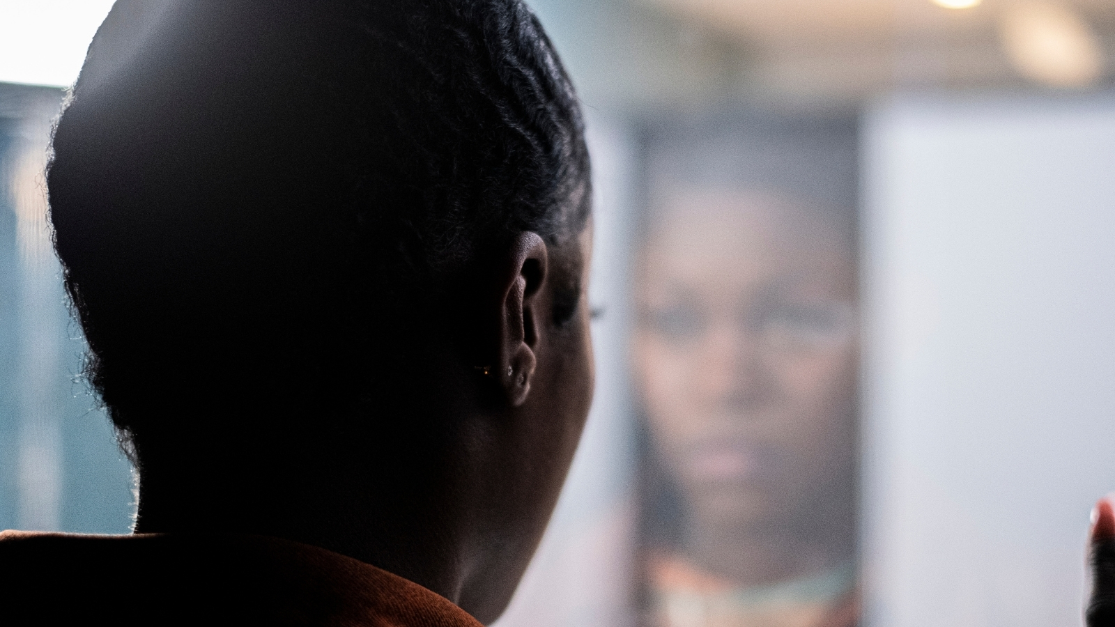 A young black woman stares into a mirror in a nightclub bathroom in the short film, Expensive Shit