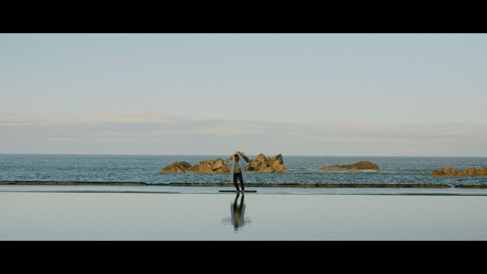 Still from Love Letters, which shows a figure walking on a beach landscape by the shore
