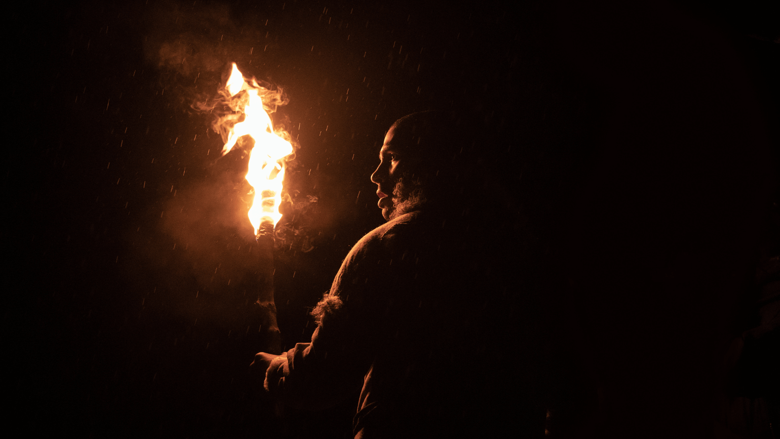 Man from the Stone Age era at night holding a fire torch.