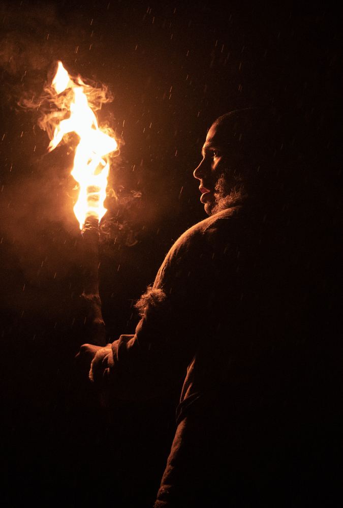 Man from the Stone Age era at night holding a fire torch.
