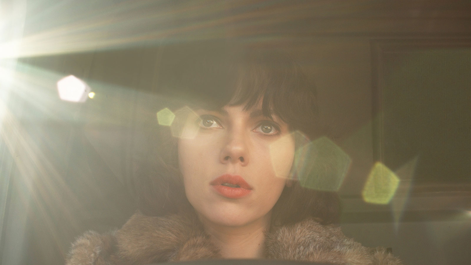 Scarlett Johansoon with black cropped hair and red lips driving in car