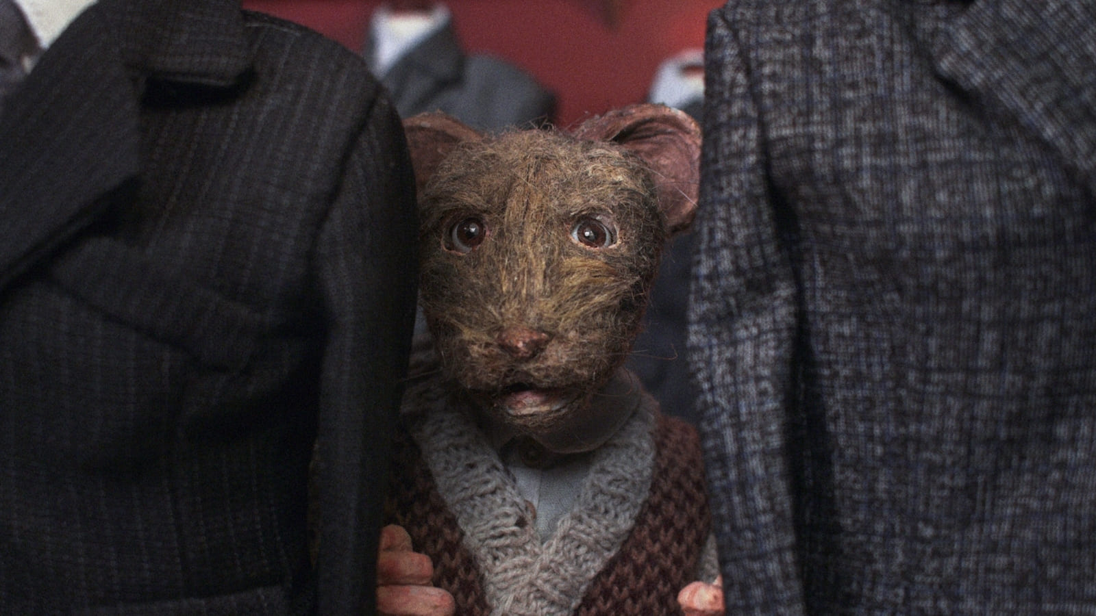 An animated mouse looks up between two suits in a tailor shop