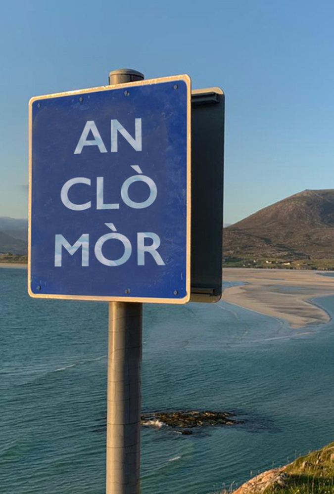 A road sign that reads An Clò Mòr. A sunny coast in the background.