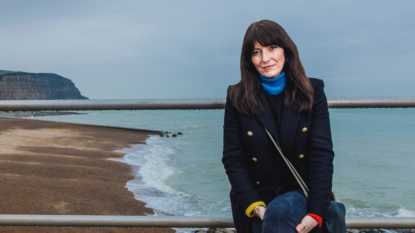 Davina sitting down with a beach behind her.