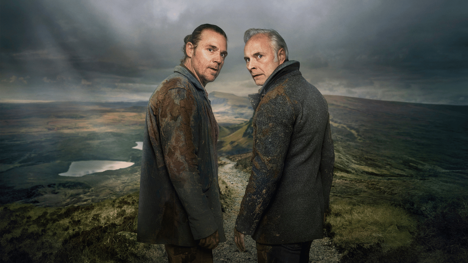 Guilt 3 promotional image. Jamie Sives and Mark Bonnar have their backs to the camera with their faces looking towards the camera with concerned expressions. They have first on their clothes and a Scottish landscape can be seen behind them.