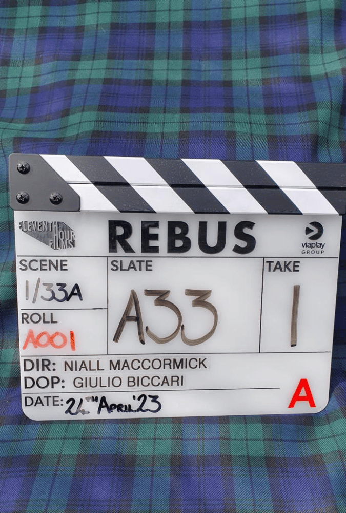 Rebus clapper board lying pn top of tartan fabric