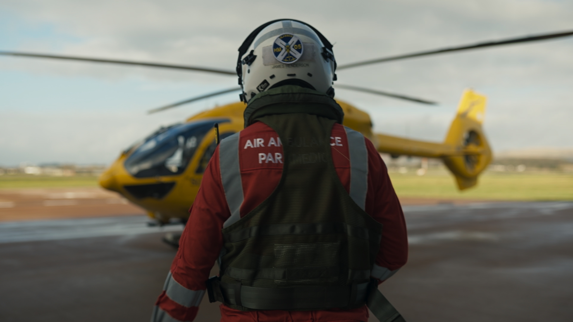 Man in ambulance uniform and helmet walking towards a helicopter
