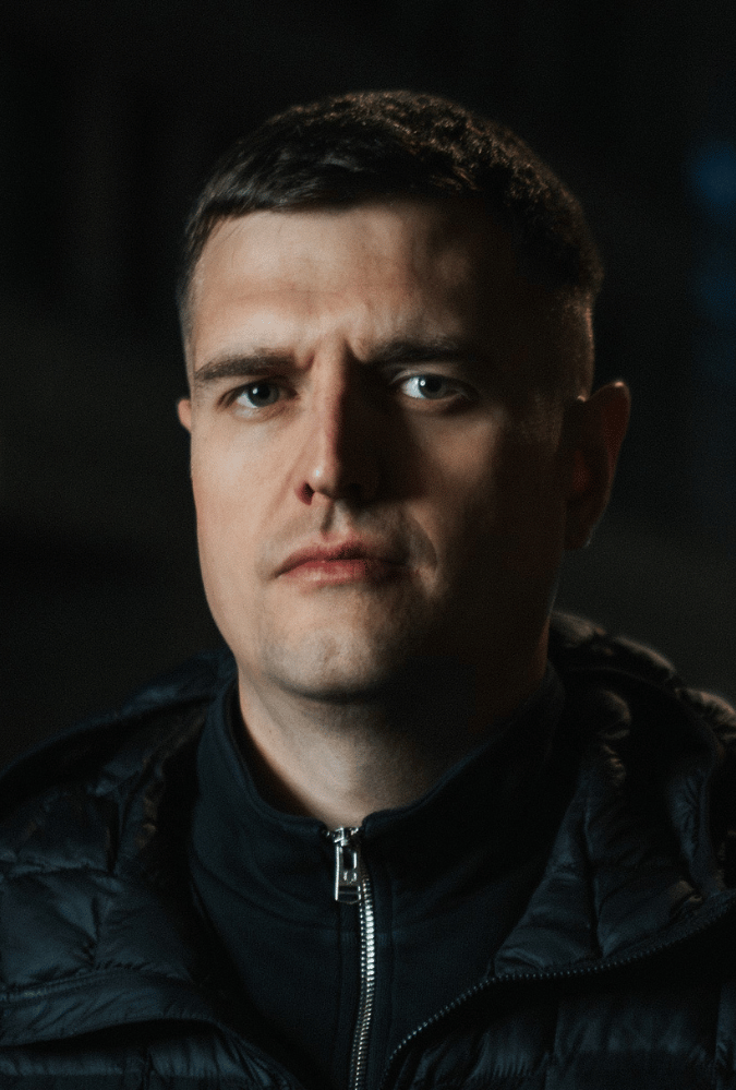 Headshot of a man scowling on a road at night.