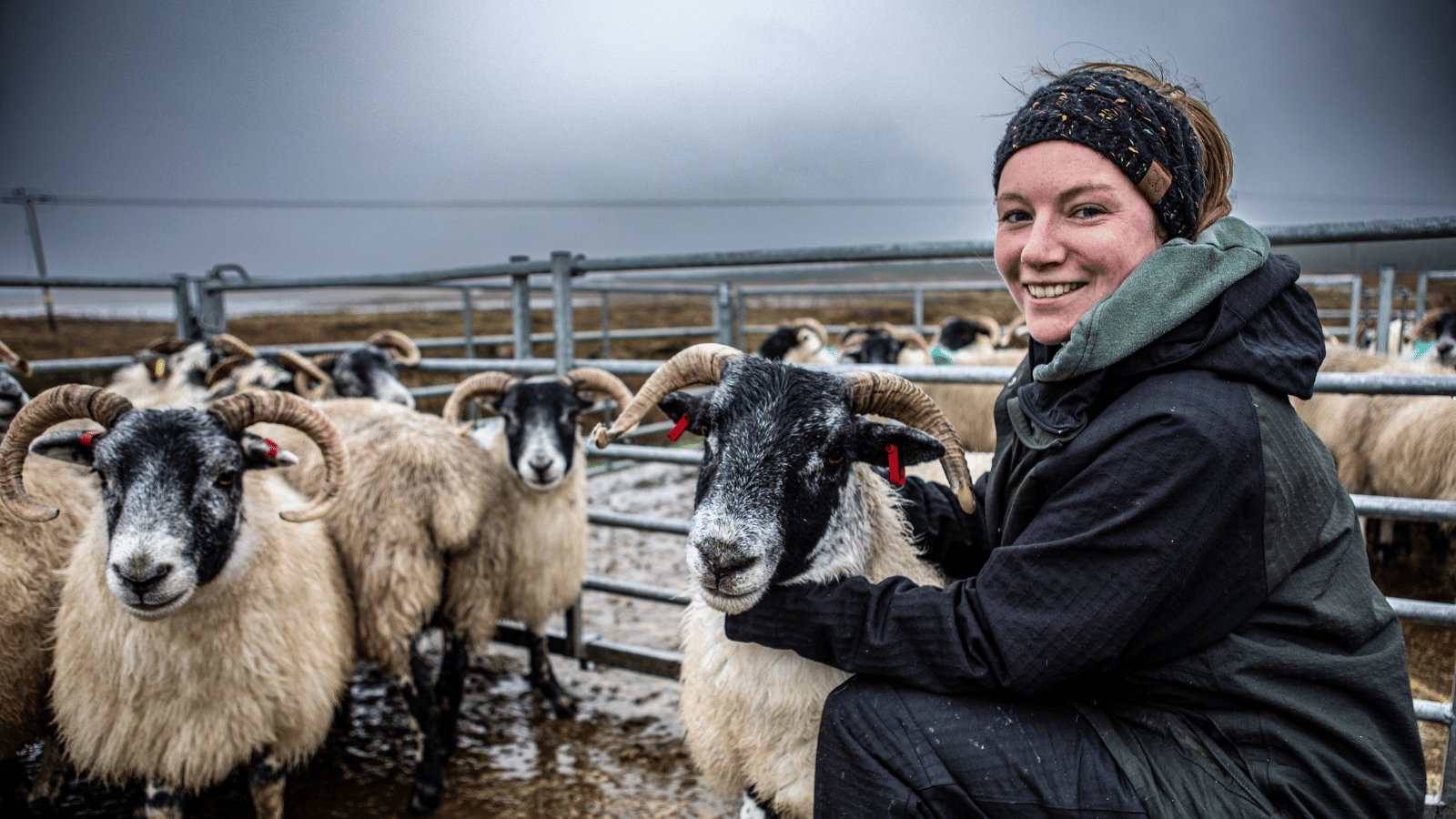 Still from This Framing Life. Carianne, Ardbhan Croft smiling outiside beside sheep pen.
