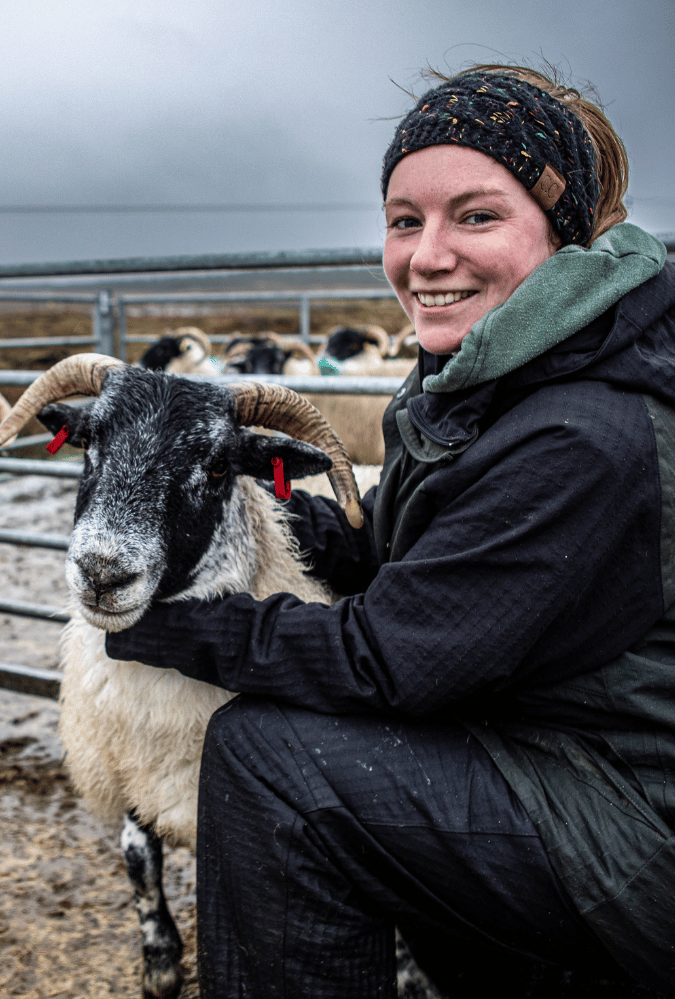 Still from This Framing Life. Carianne, Ardbhan Croft smiling outiside beside sheep pen.