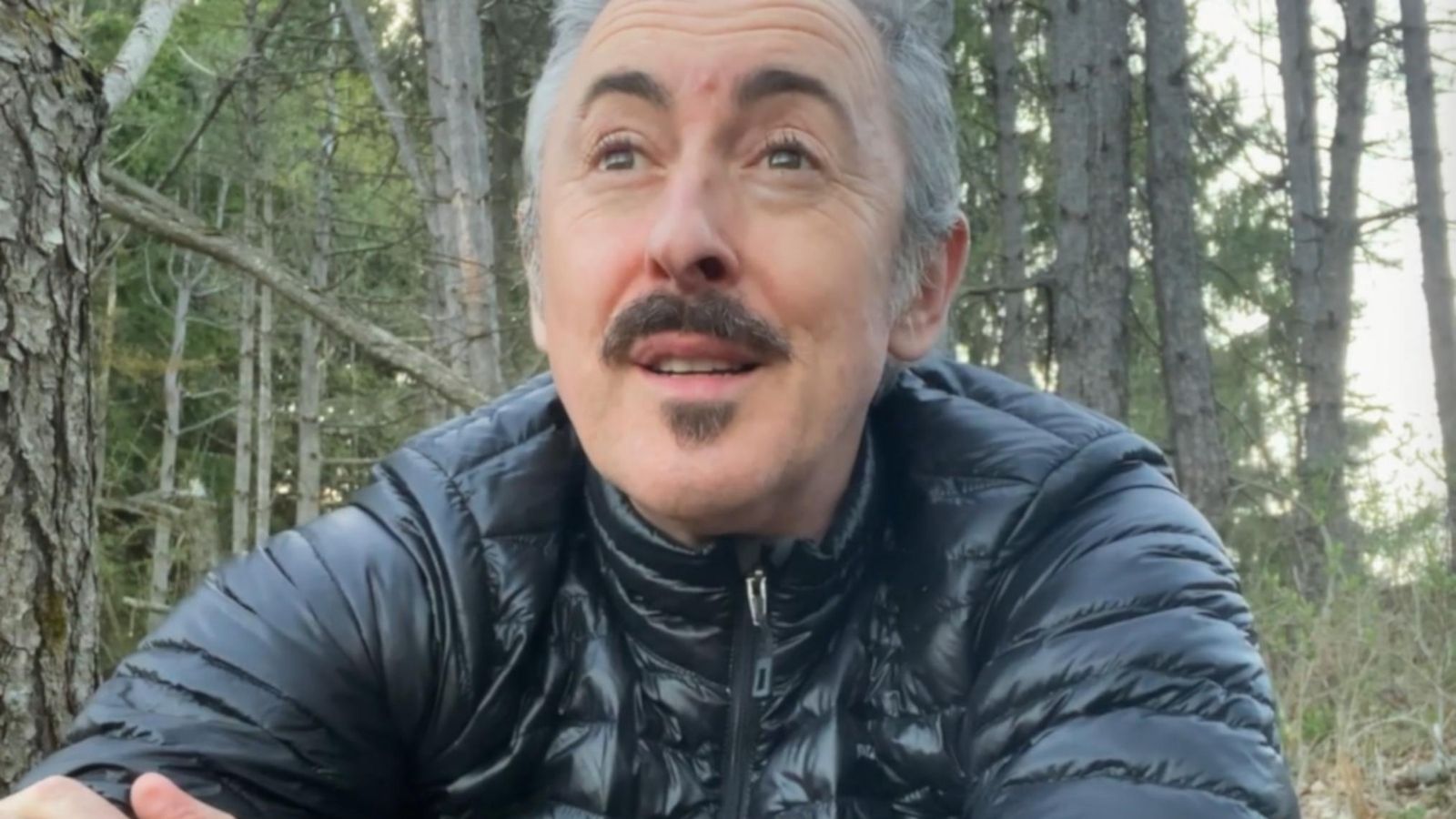 An image of actor Alan Cumming sitting outside