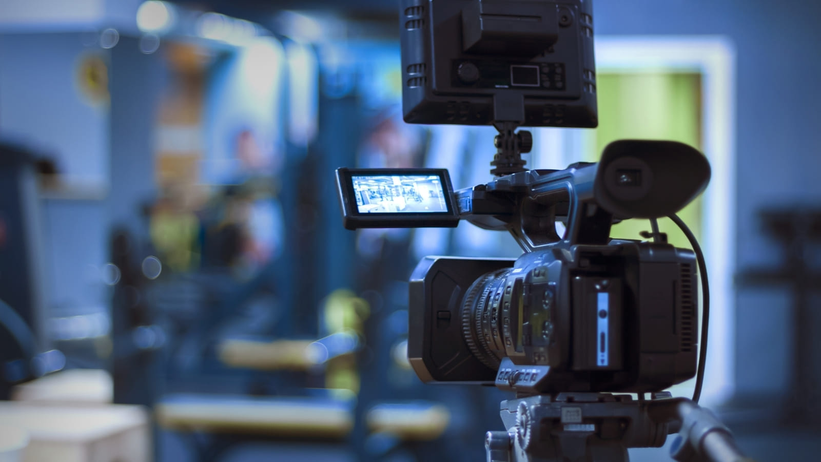 A film camera with a light attached to the top of it stands inside a lit studio