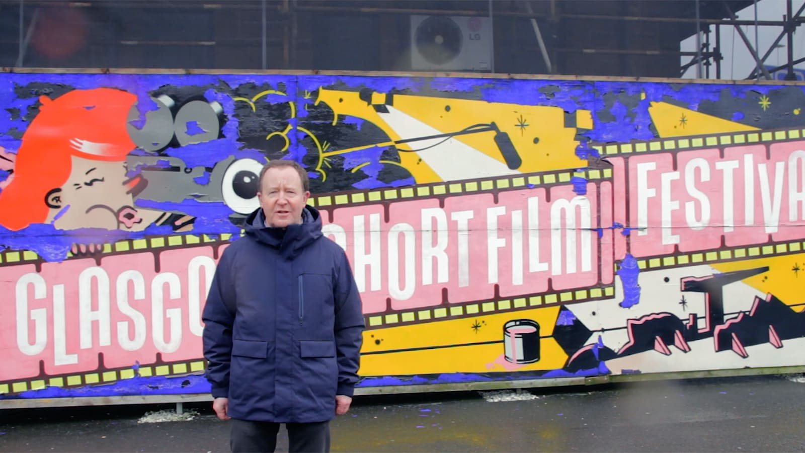 Photo of Jonathan Watson stood in front of a bus with 'Glasgow Short Film Festival' written on it