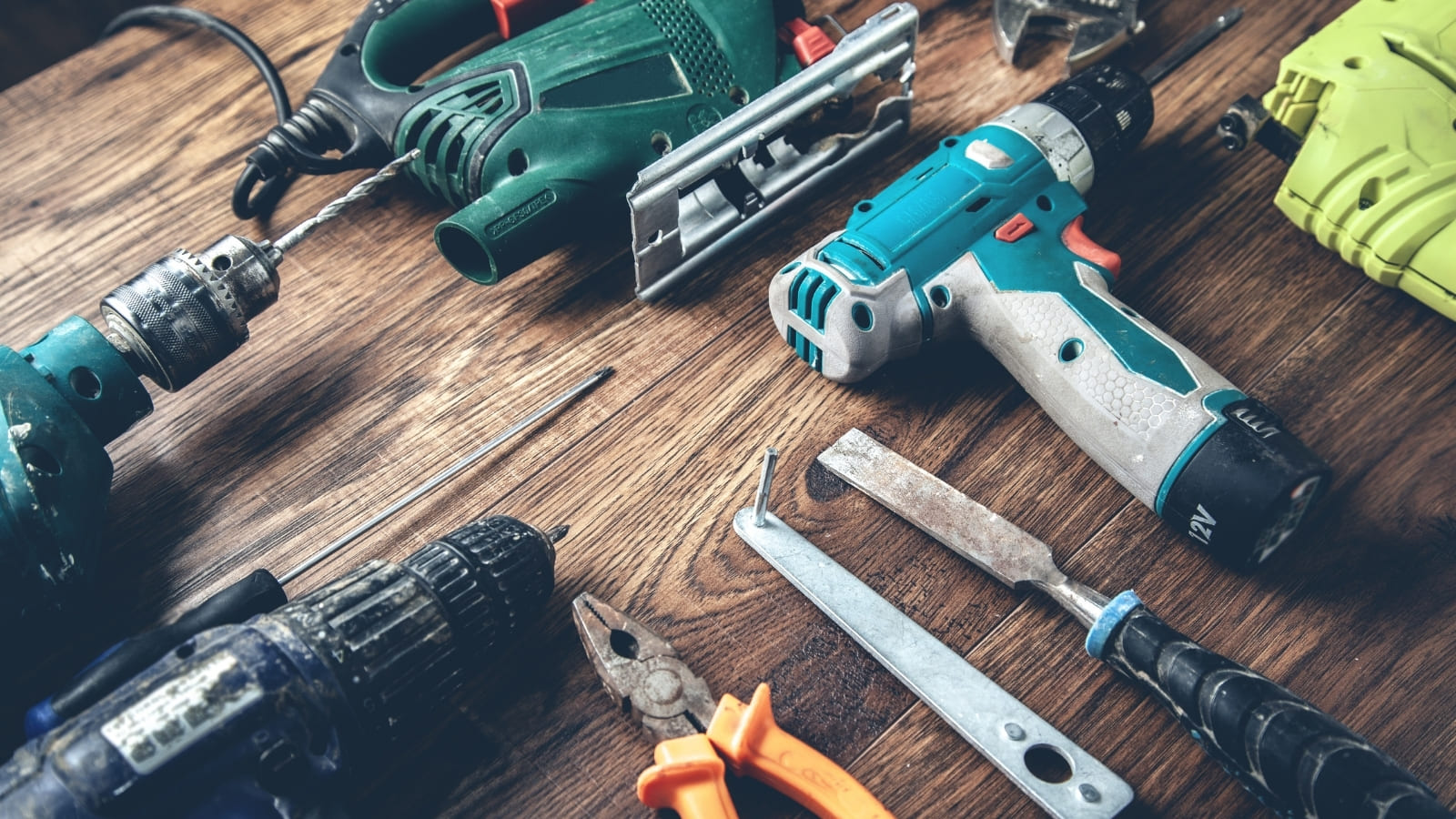 A range of tools lie together on top of a wooden work bench