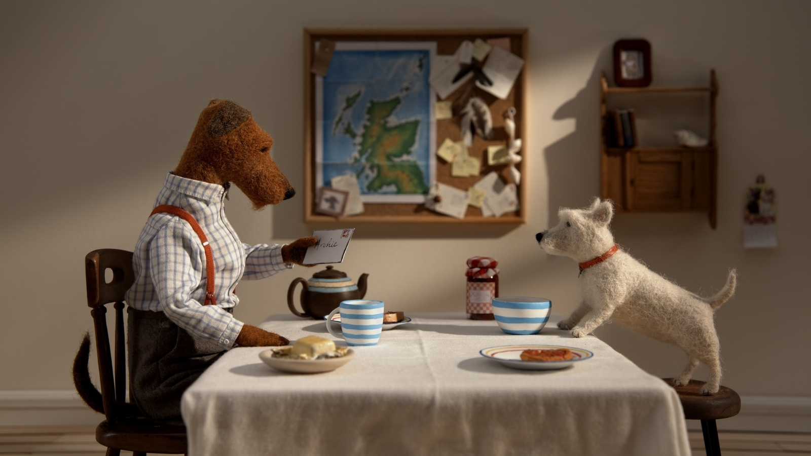 Two stop motion puppet dogs sit at a dining table