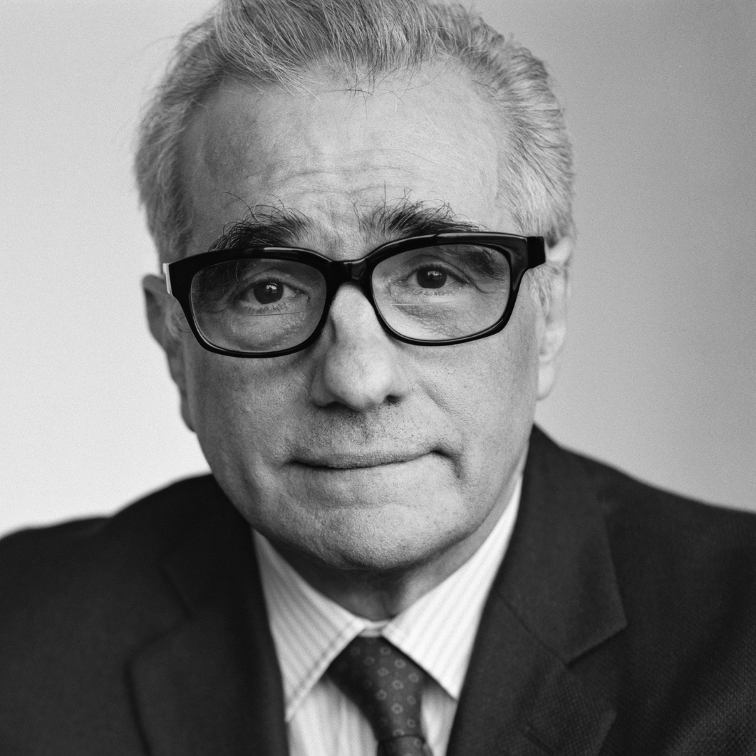 An older man with white hair and glasses wearing a striped shirt, tie and black jacket. This is a headshot of Martin Scorsese.