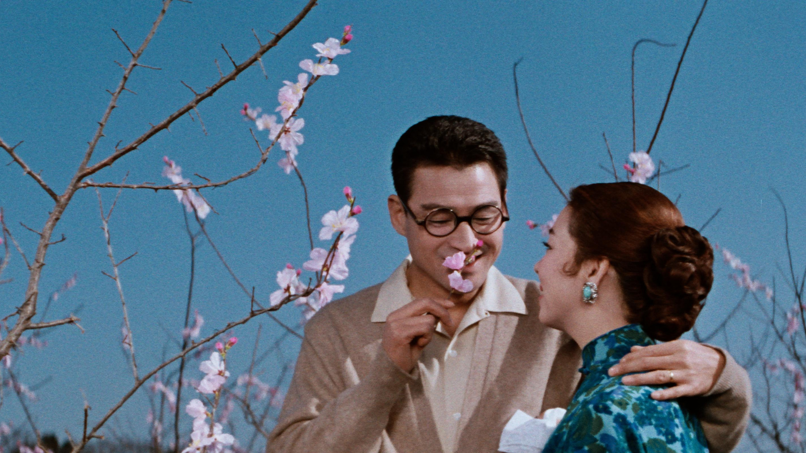 A still from The Wandering Princess Tanak. A man and a woman stand together next to a blossom tree.