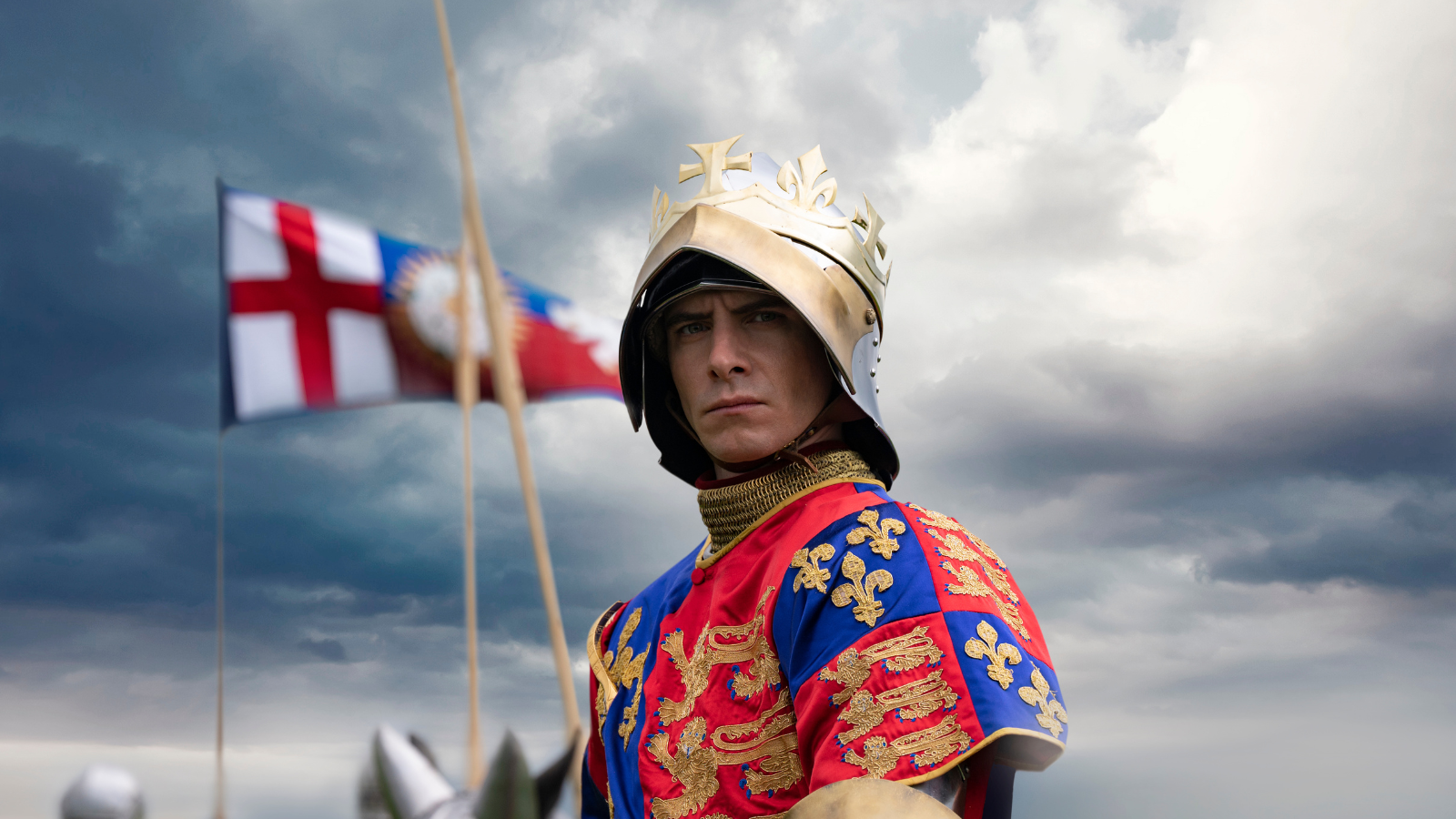 A still from The Lost King. Harry Lloyd dressed in Tudor fashion including a helmet, crown and chainmail, sitting on a horse.