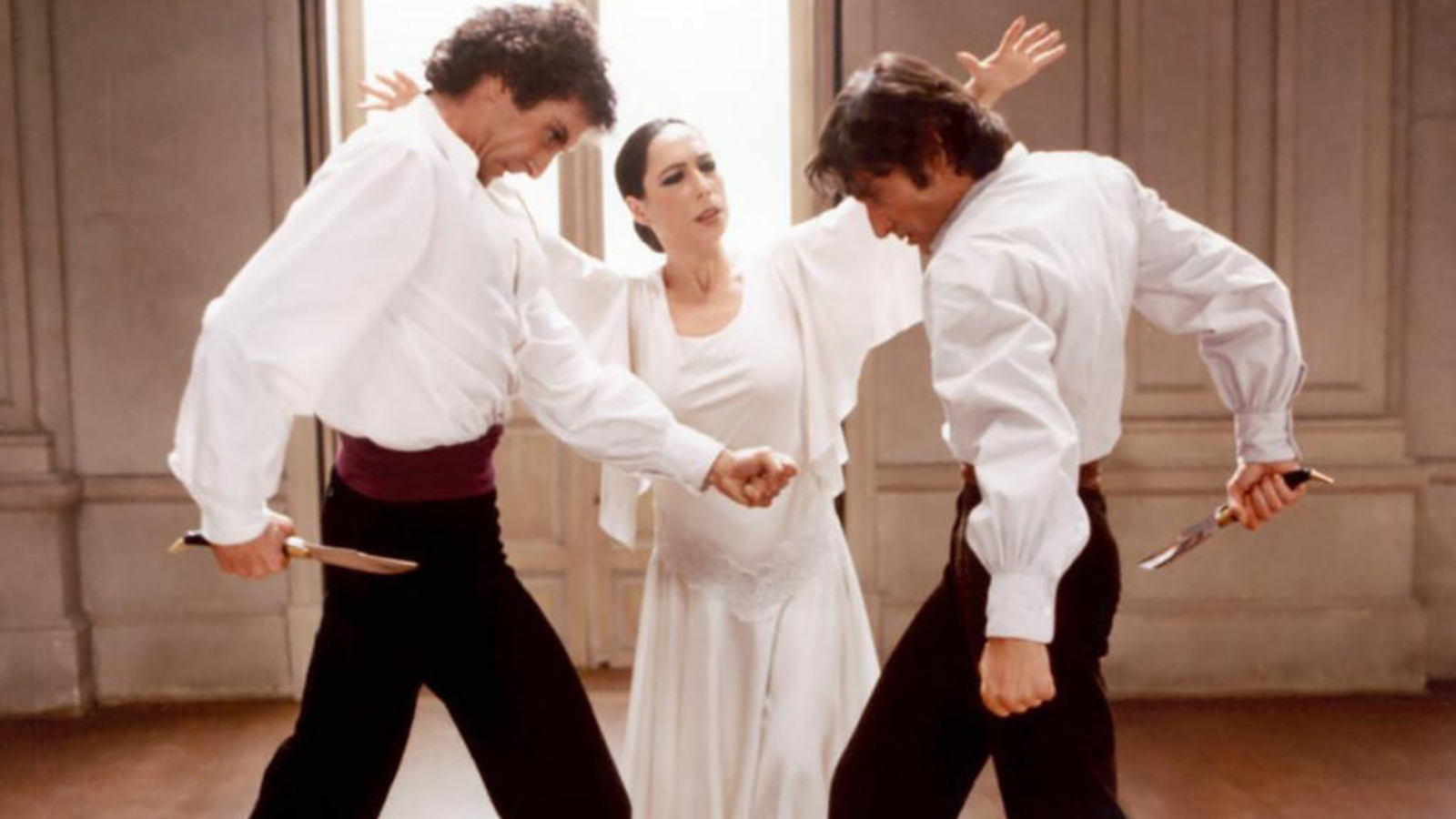 Still from Bodas de Sangra. A woman and two men dressed in black and white standing opposite each other while dancing.