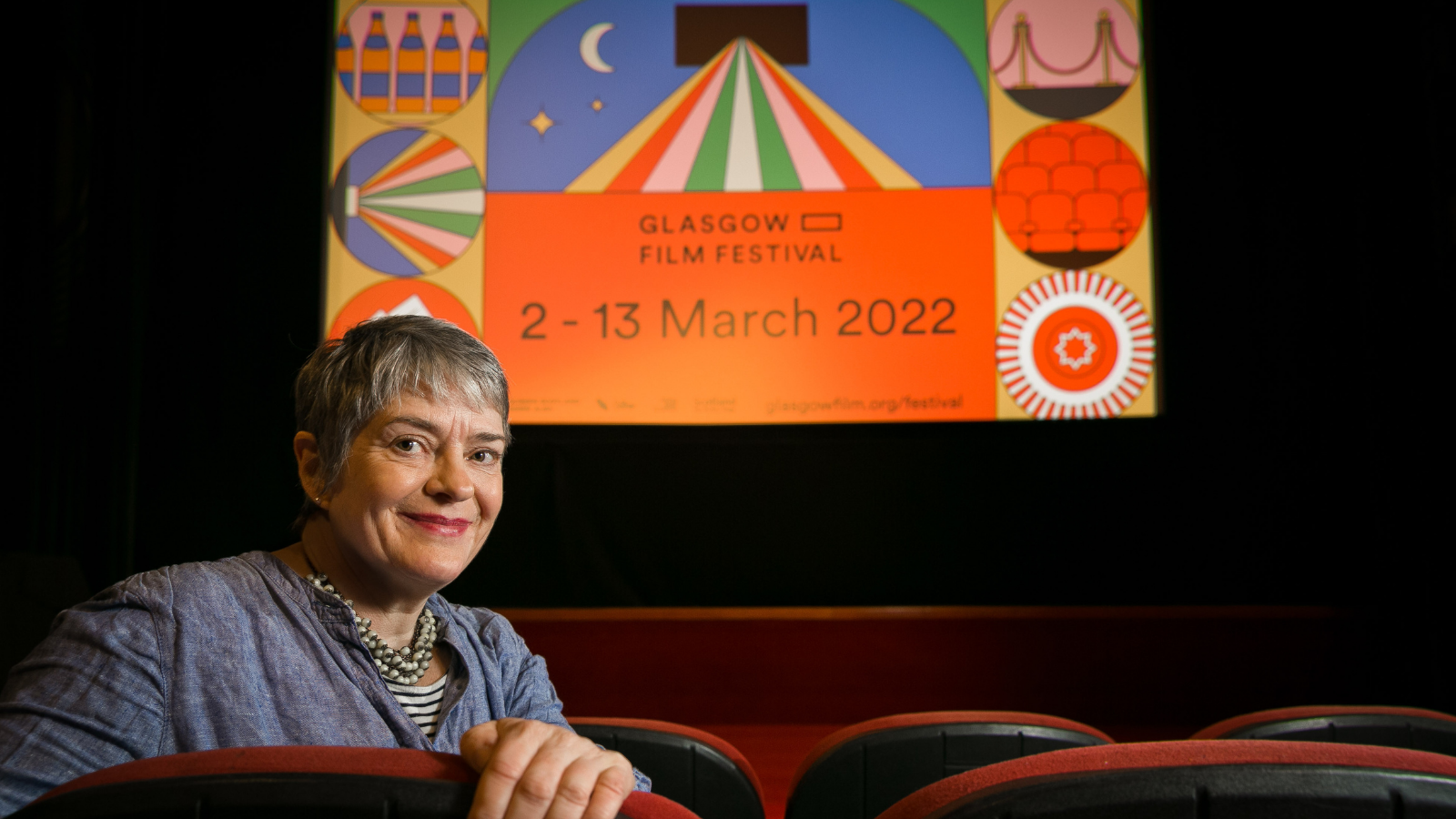 GFF Co-Director Allison Gardner is pictured in front of a large screen displaying the dates for GFF 2022: 2 - 13 March 2022.