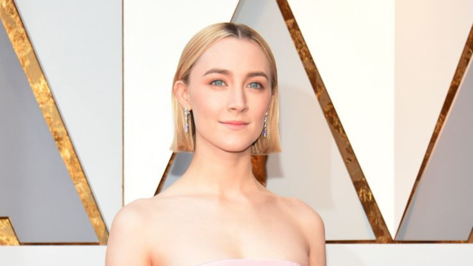A woman with short blonde hair - the actress Saiorse Ronan - in a pink strapless dress at a red carpet event (The Oscars).