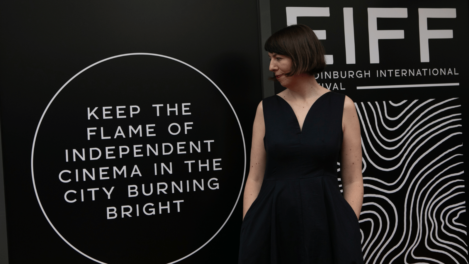 Kate Taylor at EIFF Opening Night. Stood in front of EIFF branded sign saying "keeping the fame of independent cinema alive"