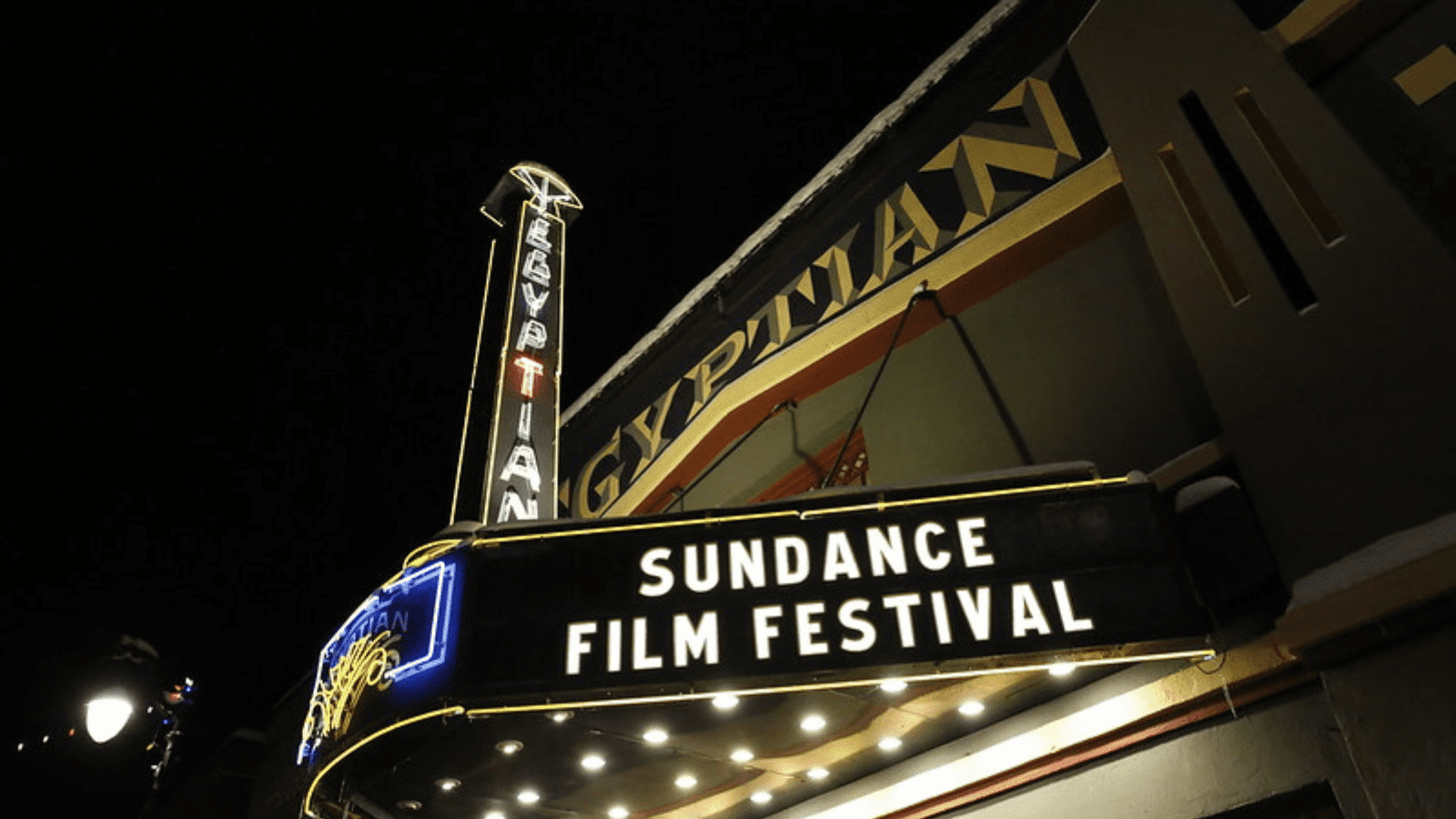 A image looking up at the 2020 Egyptian Theatre at night in the dark, which has a sign on it, which reads Sundance Film Festival in bright letters