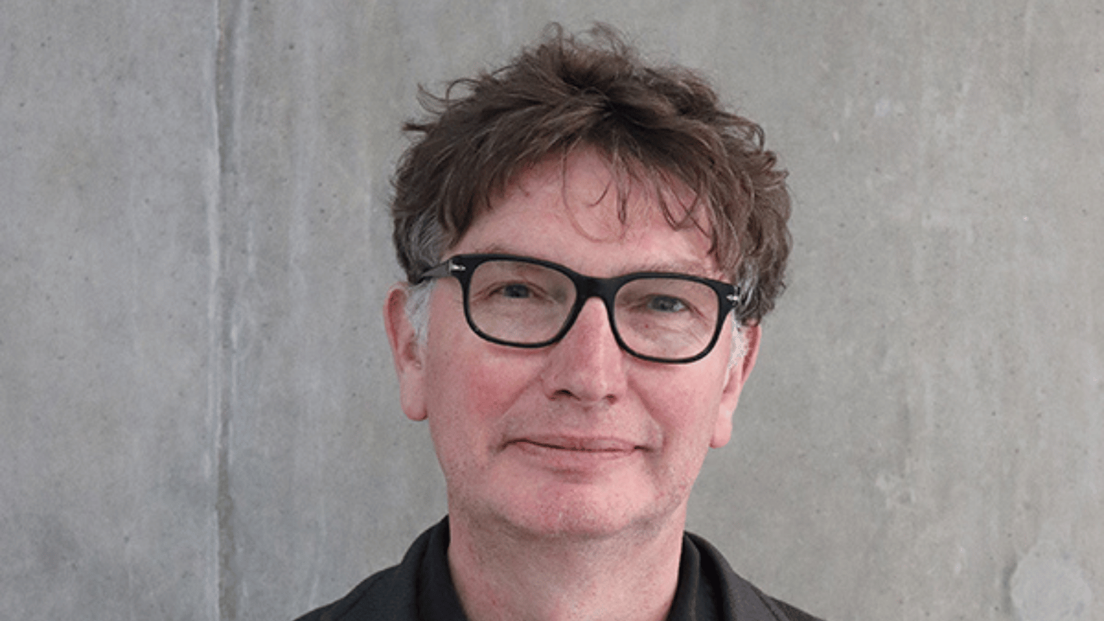 Headshot of Andrew Macdonald who wears glasses and has short brown hair