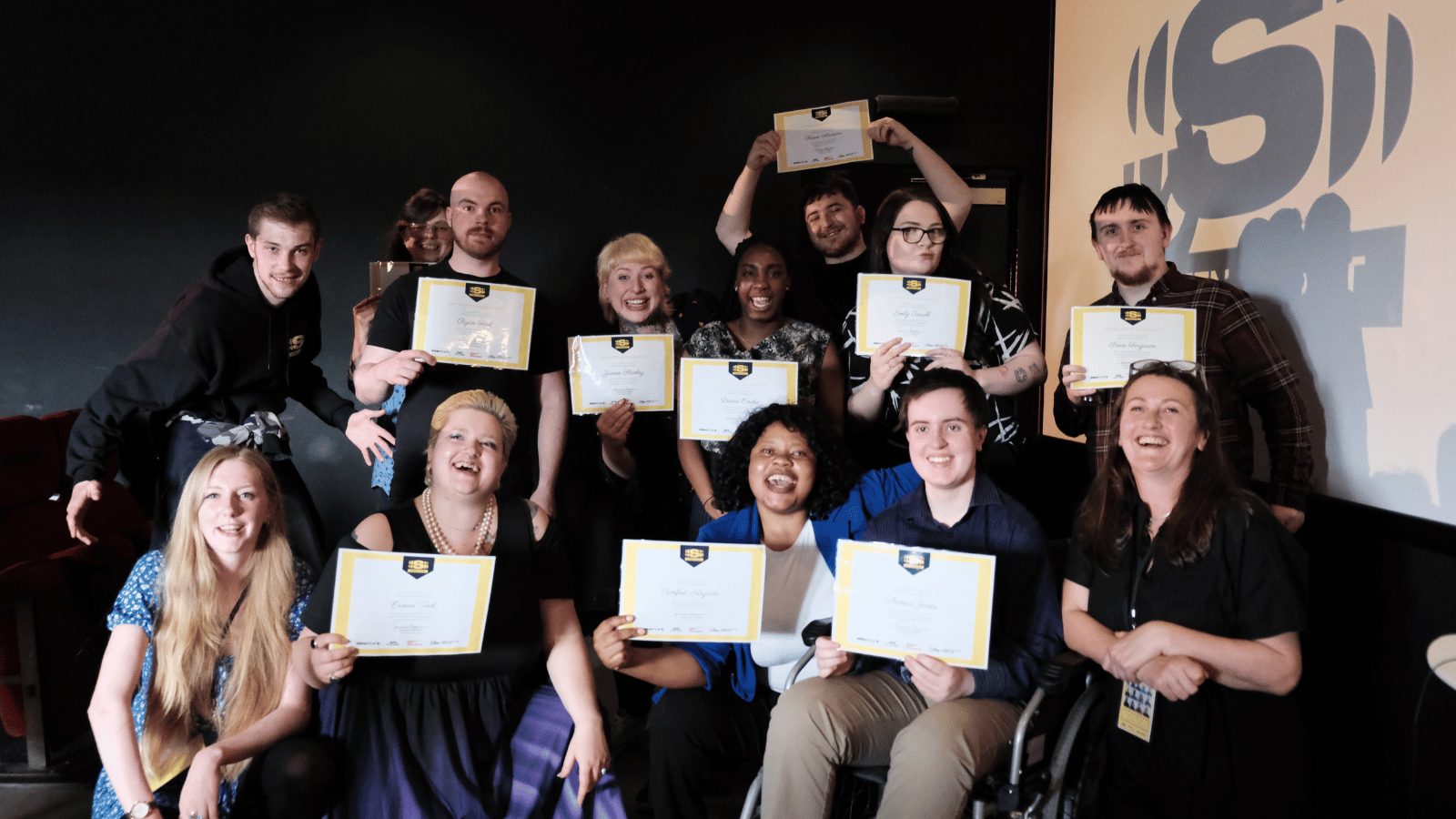 Screen Start graduates, courtesy of GMAC Film. The group sit over two rows and hold certificates up to the camera
