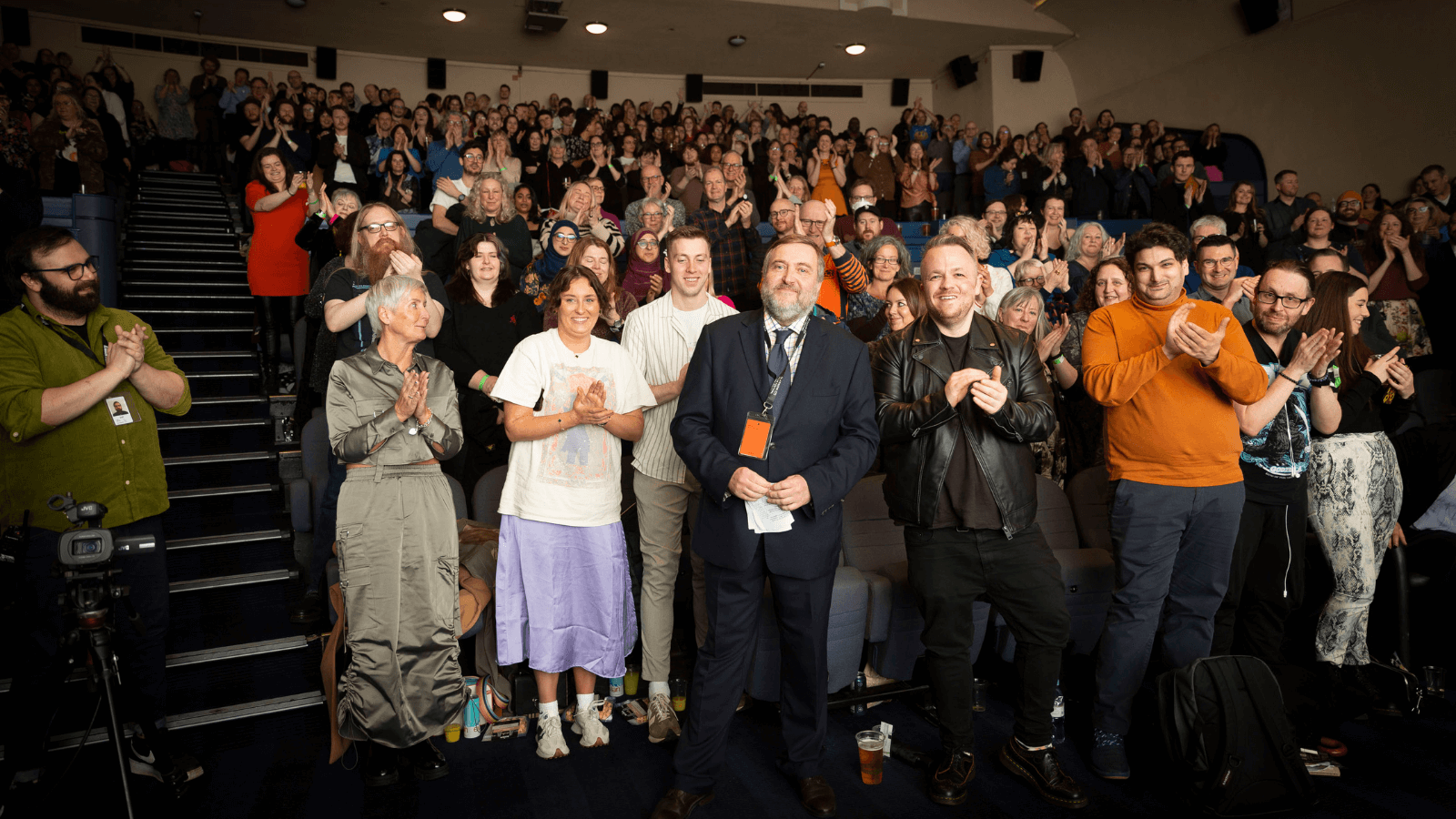 Allan Hunter stands in front of a crowd on their feet at Glasgow Film Festival