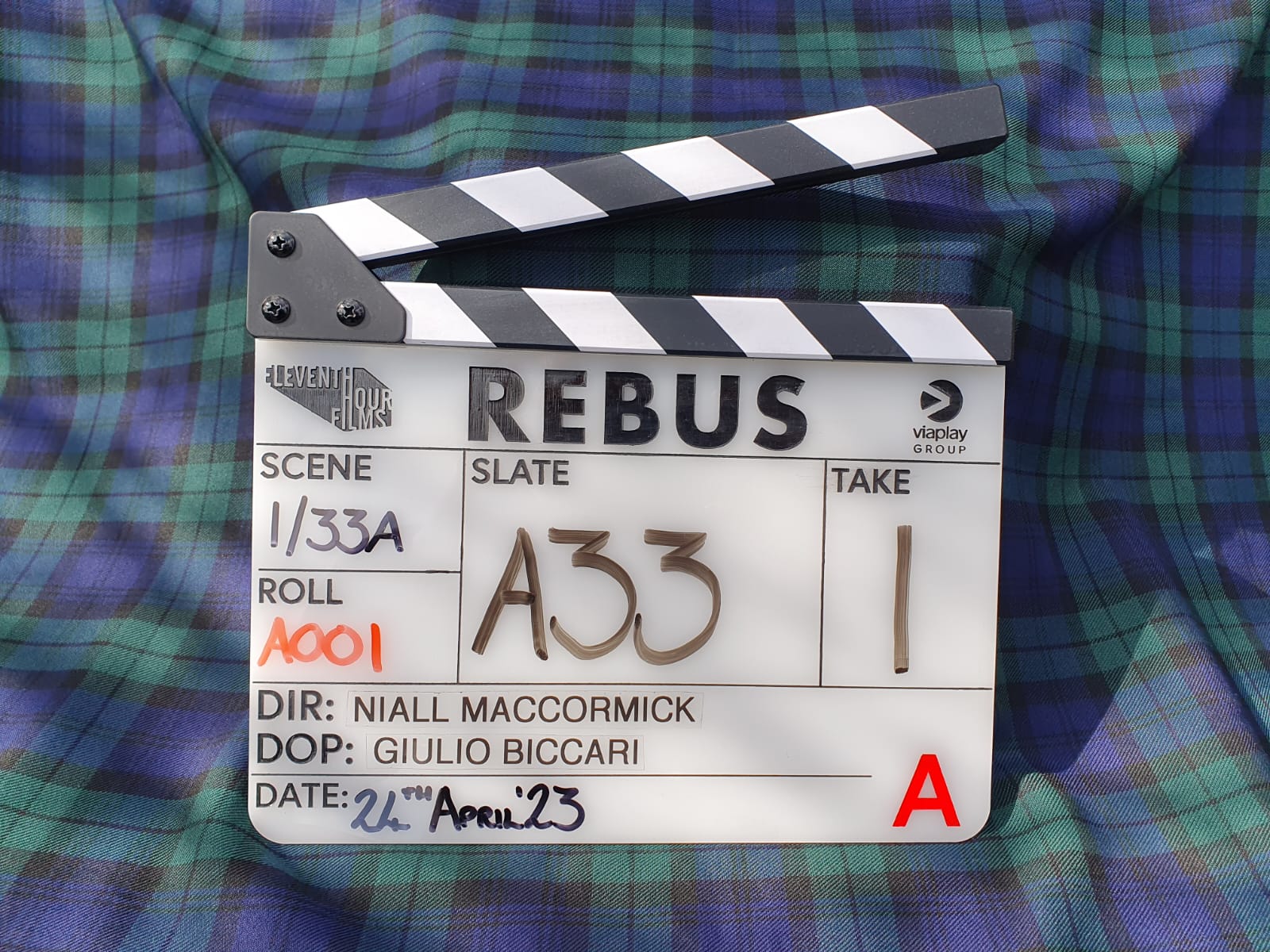 Rebus clapperboard lying on top of tartan fabric