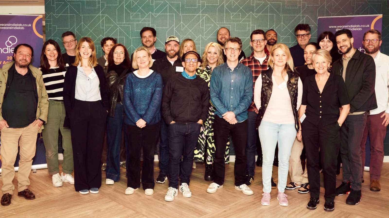 A group of people stand in a row, smiling at the camera