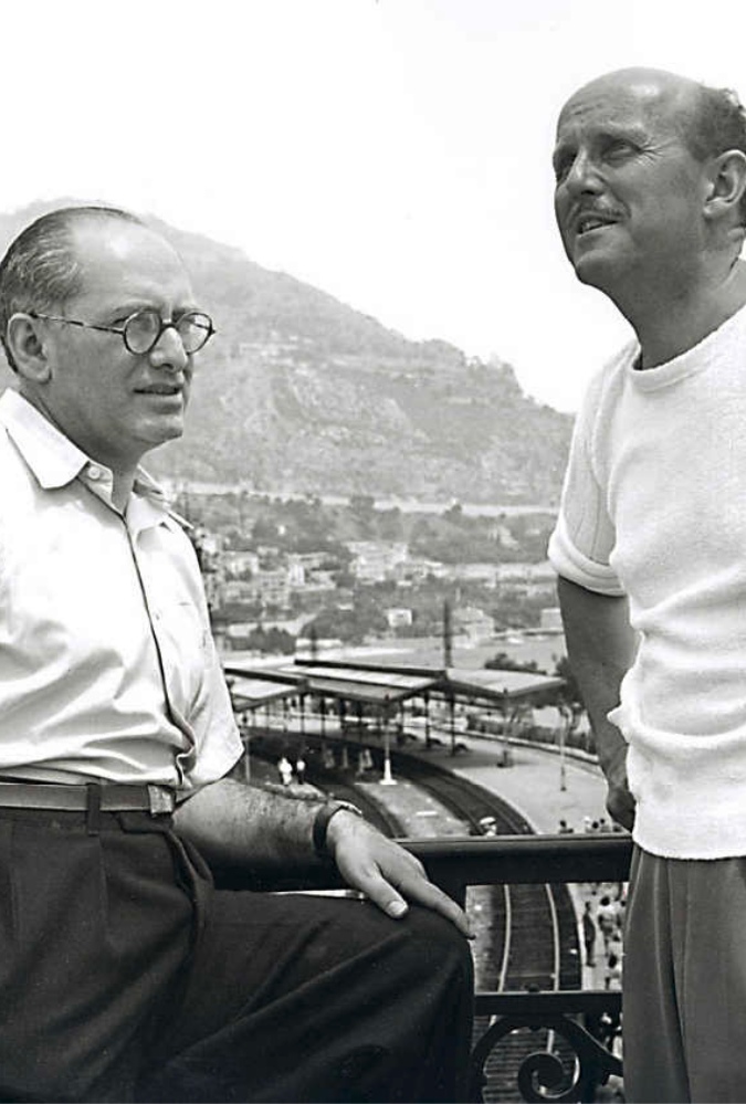 A black and white image of Michael Powell and Emeric Pressburger, who stand leaning on a balcony on the set of the film The Red Shoes,