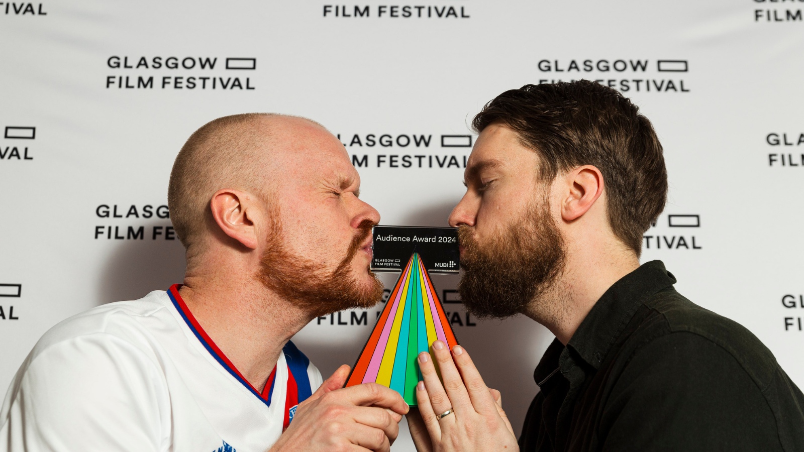 Winners of the Glasgow Film Festival Audience Award Kari Vidarsson and Smari Gunn kiss either side of the award as they hold it between them