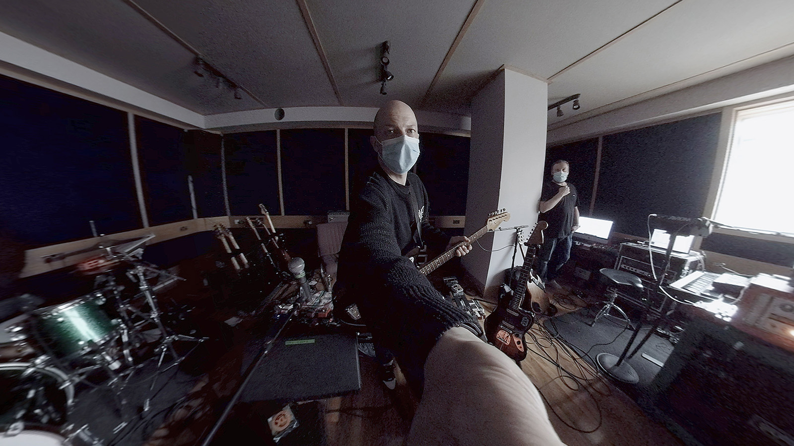 Still from Mogwai: IF THE STARS HAD A SOUND. Band member Stuart Braithwaite in the studio wearing a mask and holding a guitar.