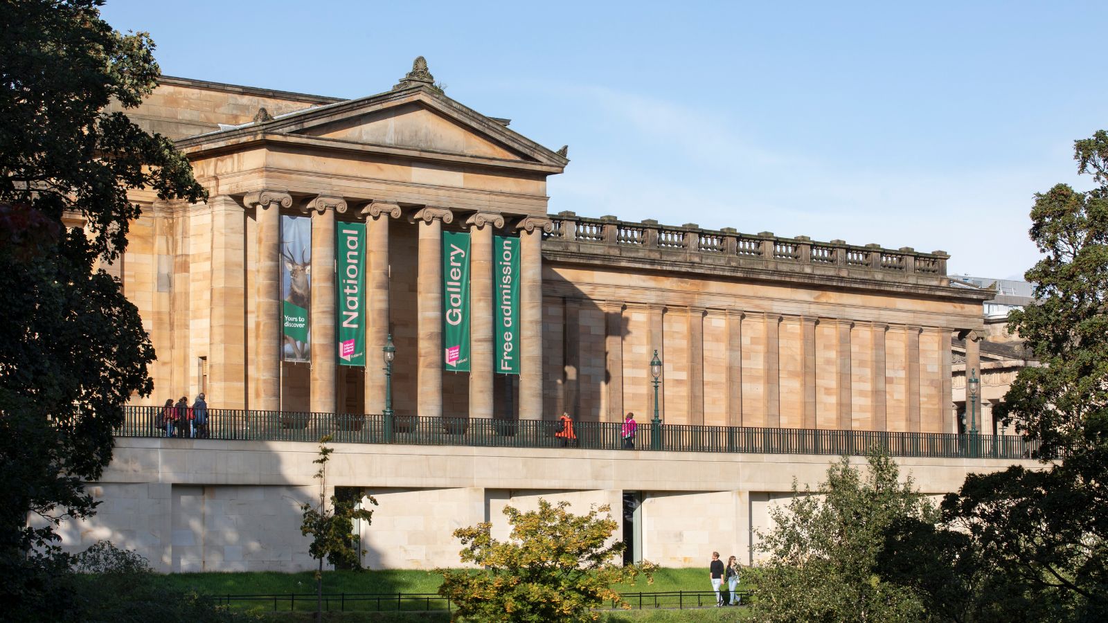 A large stone building with columns at the front in situated in outdoors with trees around it