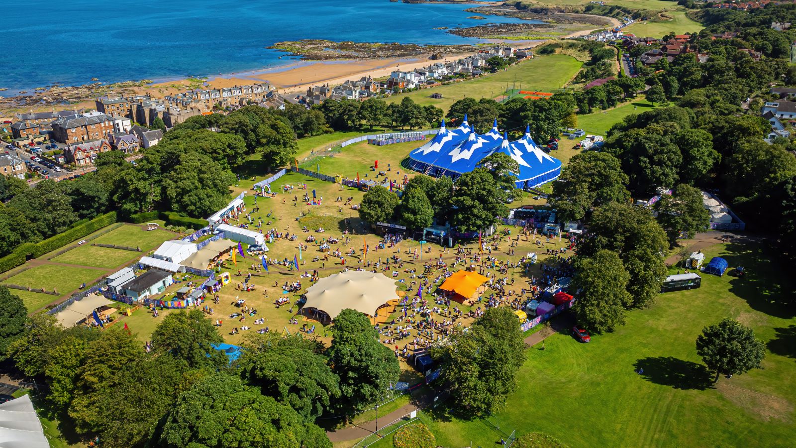 Drone shot of the coat at East Lothian, showing grass, trees and pop up buildings.