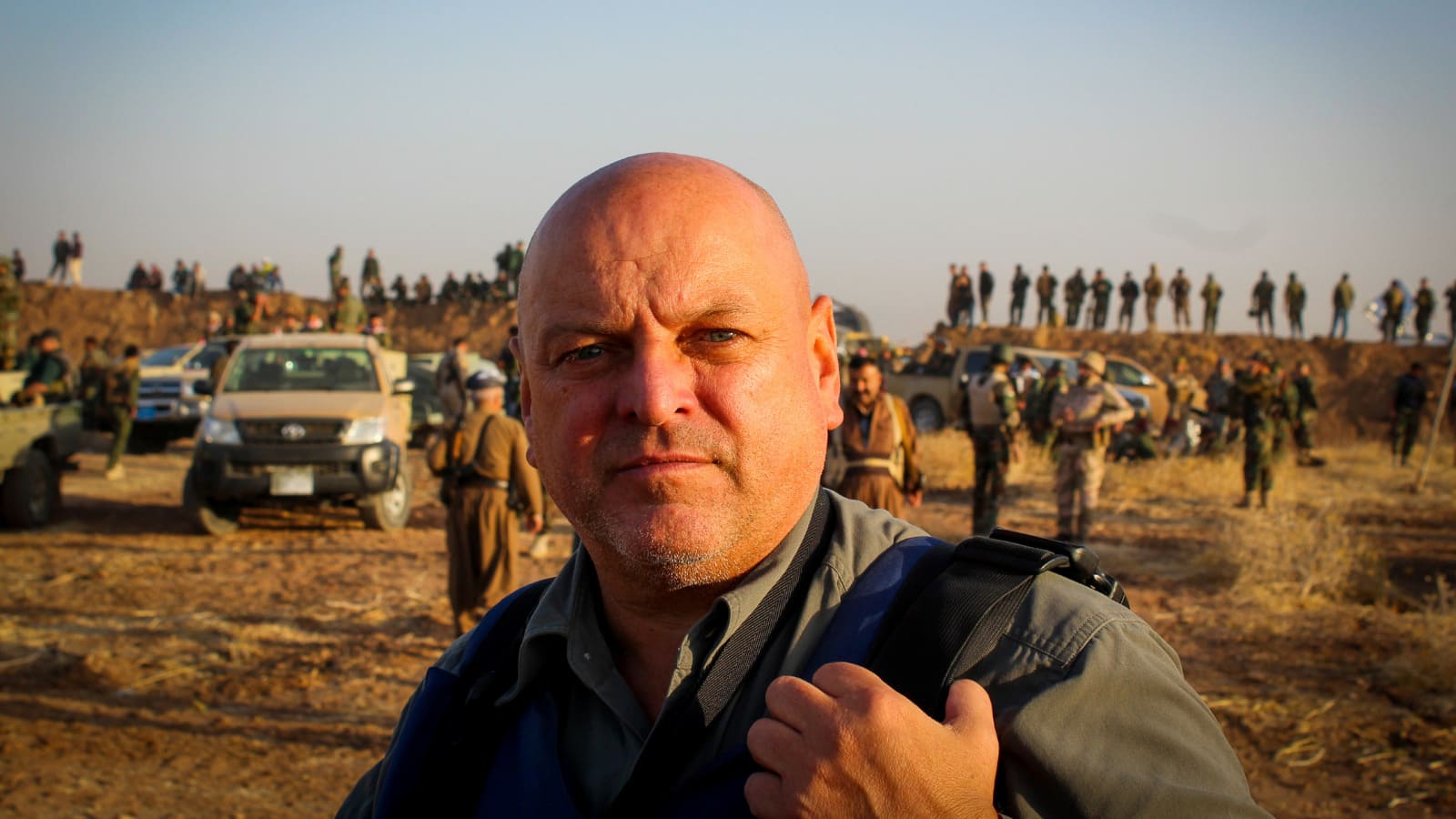 Fillmaer David Pratt looking at the camera with army troops seen in the background.