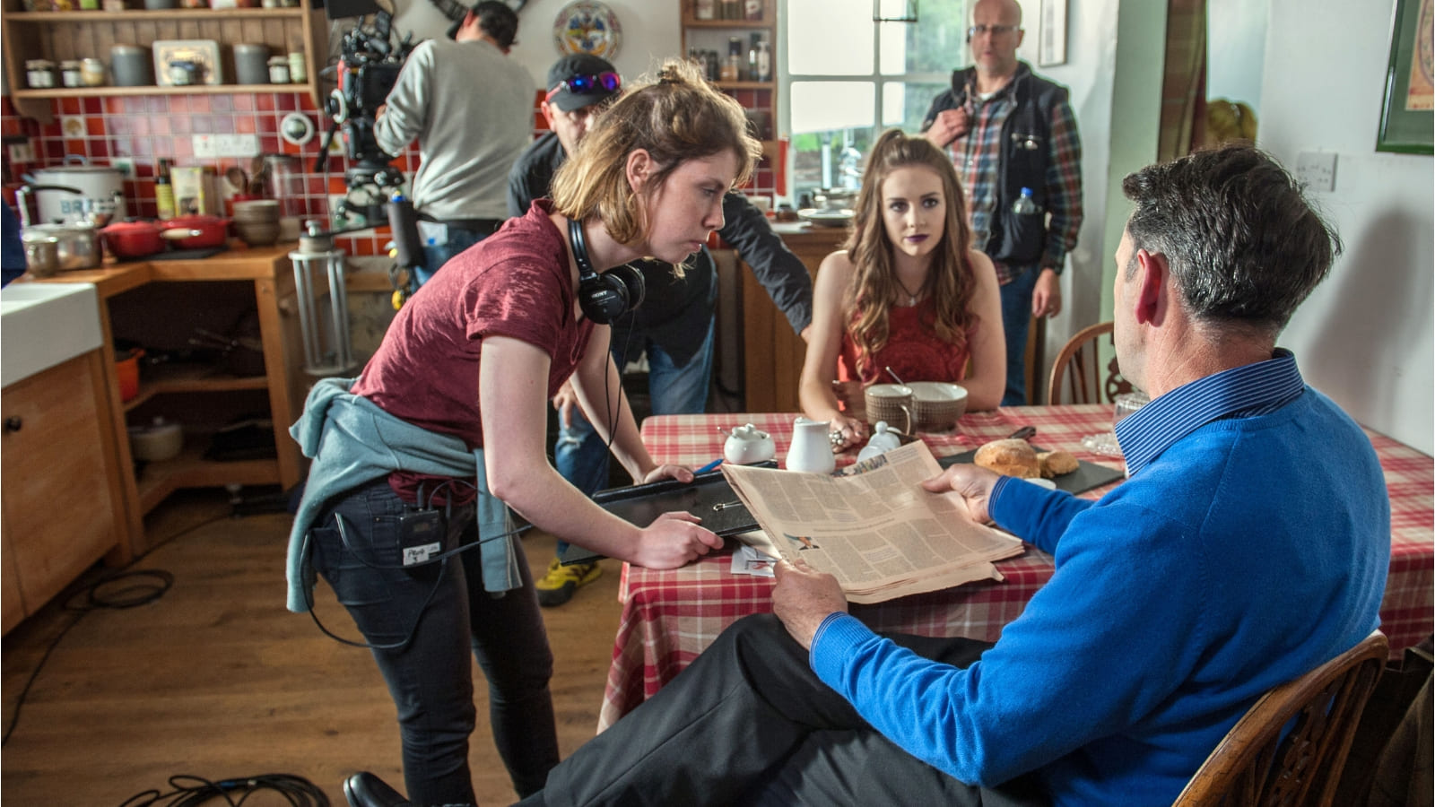 On the set of TV Show, Bannan, people stand around a table in a scene set in a kitchen