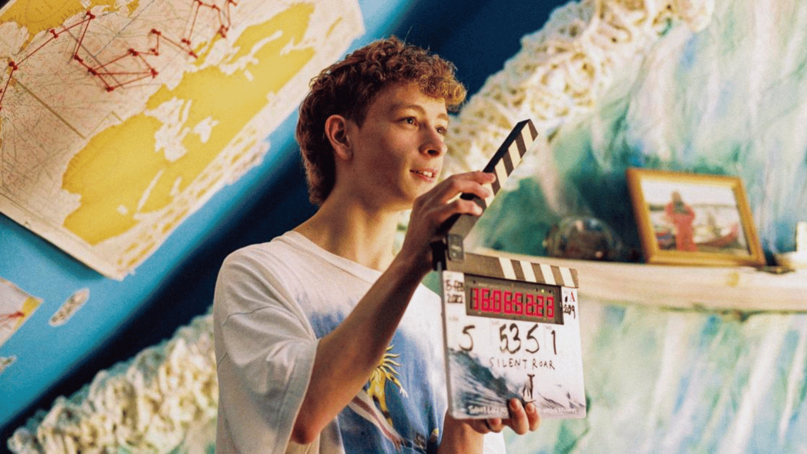 An actor on the set of Silent Roar holding a clapper board