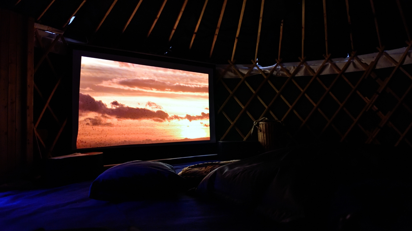 A screen plays a film in a small and cosy yurt owned by Cinemor Mhor