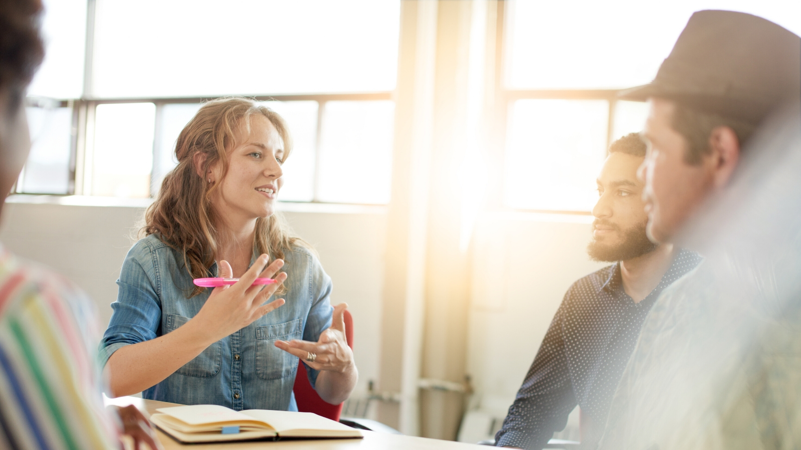 Three creative people sit in discussion at a table