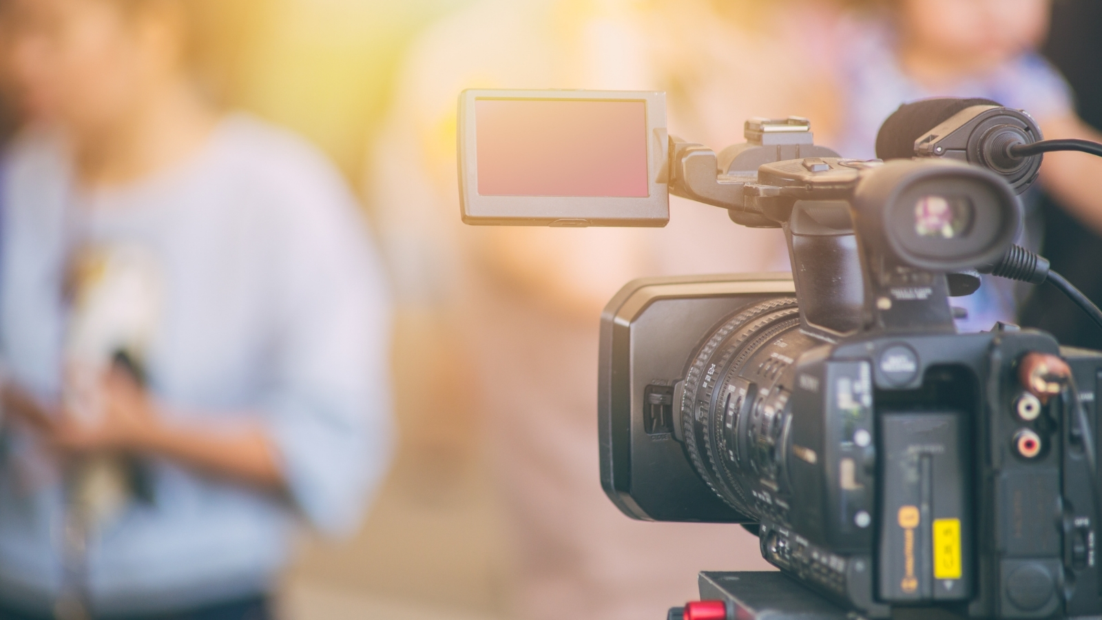 Close up image of a film camera with a person standing out of focus in the distance